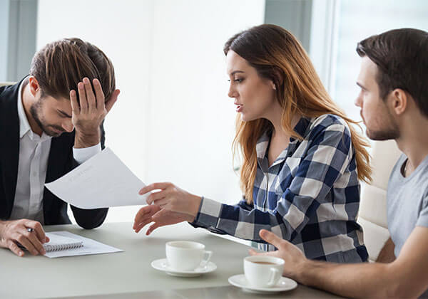 Young couple with realtor discussing contract mistakes
