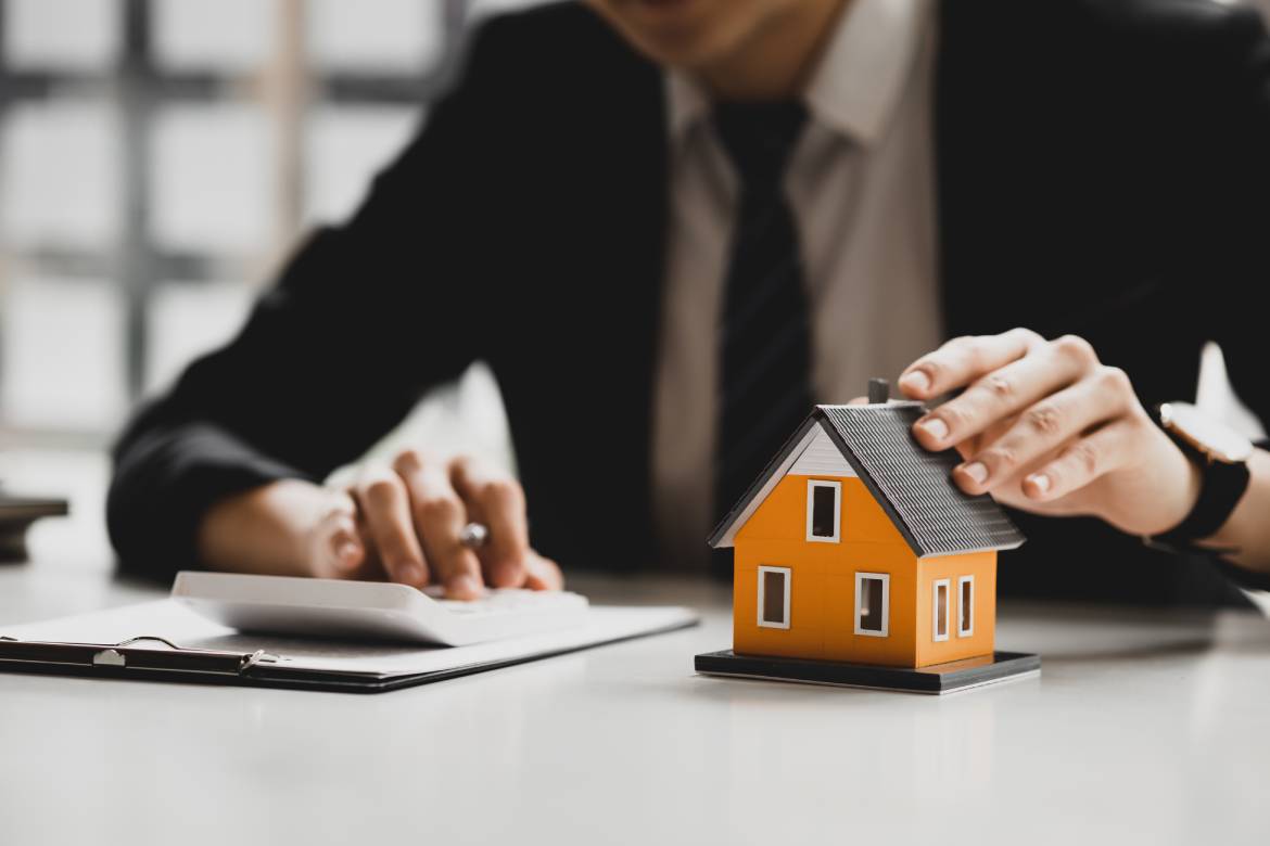Orange mini house model, housing project, salesperson calculates the price and explains the transaction details to customers and gives advice to help with bank loans. Real estate trading concept.