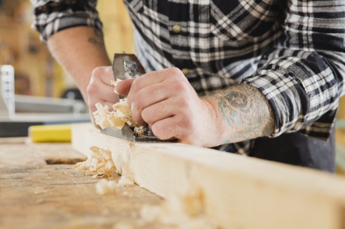 Carpenter work with plane on wood plank