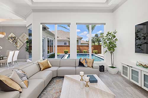 A cozy living room with a large sectional couch and a flat-screen television mounted on the wall.