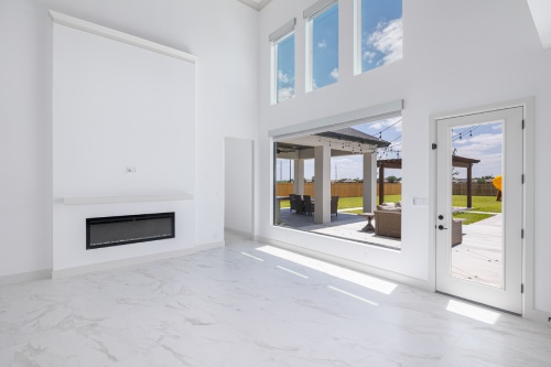 A bright white living room featuring a cozy fireplace and large sliding glass doors leading to an outdoor space.